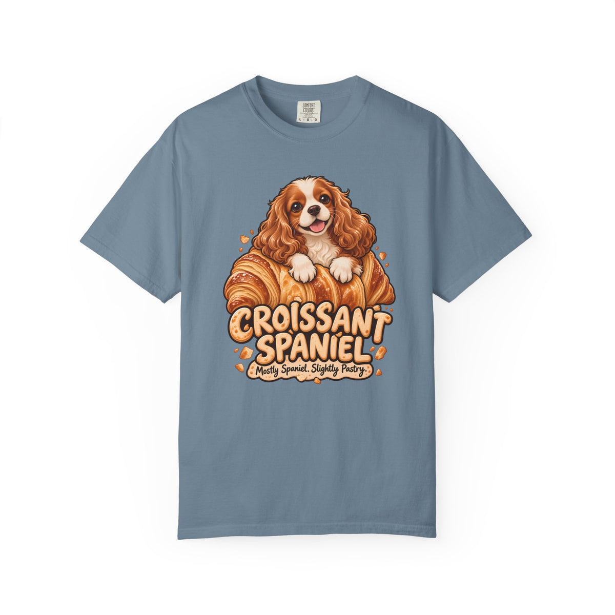 Blue Croissant Spaniel T-shirt, featuring a Cavalier spaniel combined with a golden croissant and the wording “Croissant Spaniel — Mostly Spaniel. Slightly Pastry.”