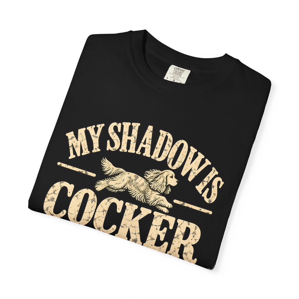 Folded Black T-shirt showing the Cocker Spaniel illustration and “My shadow is cocker shaped” lettering.