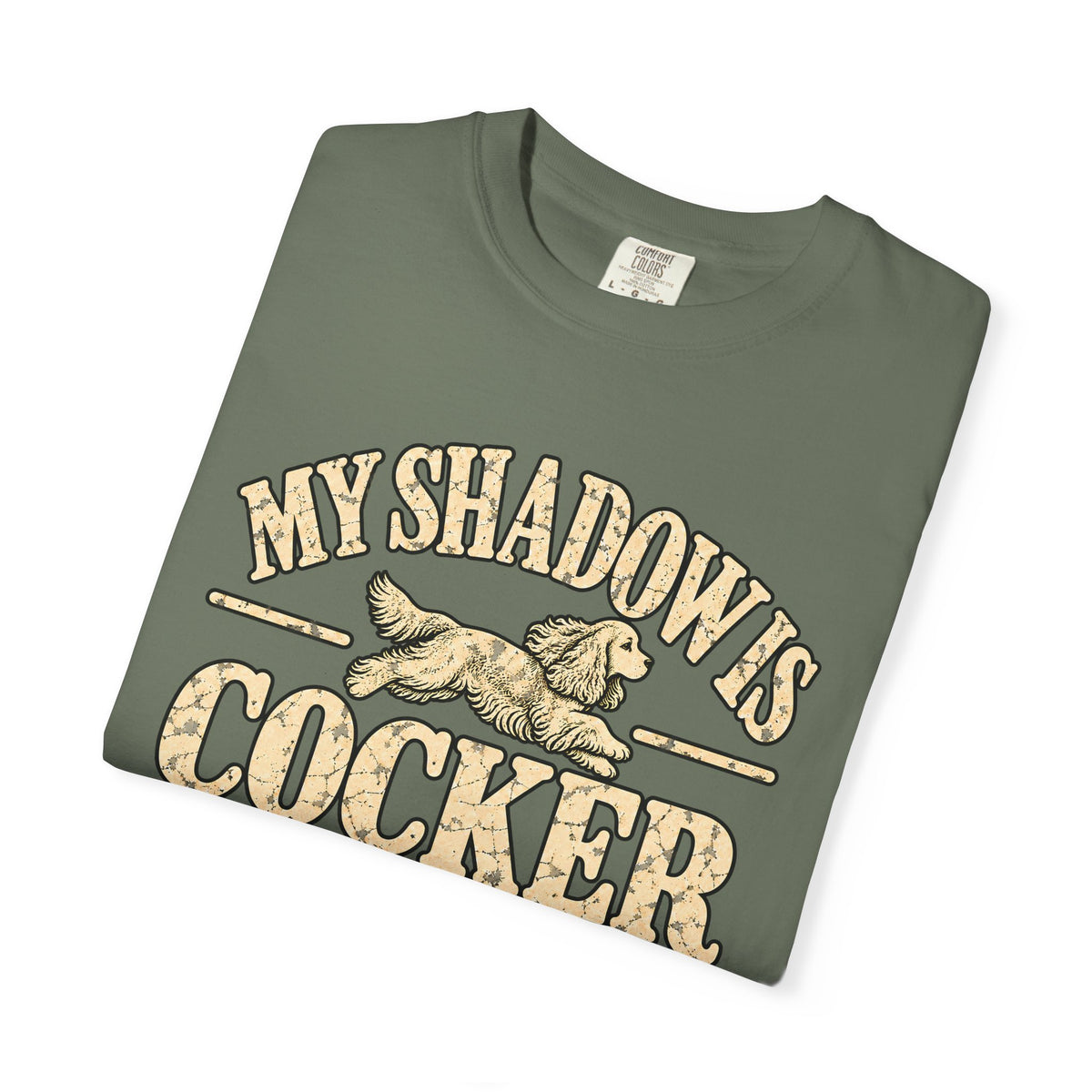 Folded Moss T-shirt showing the Cocker Spaniel illustration and “My shadow is cocker shaped” lettering.