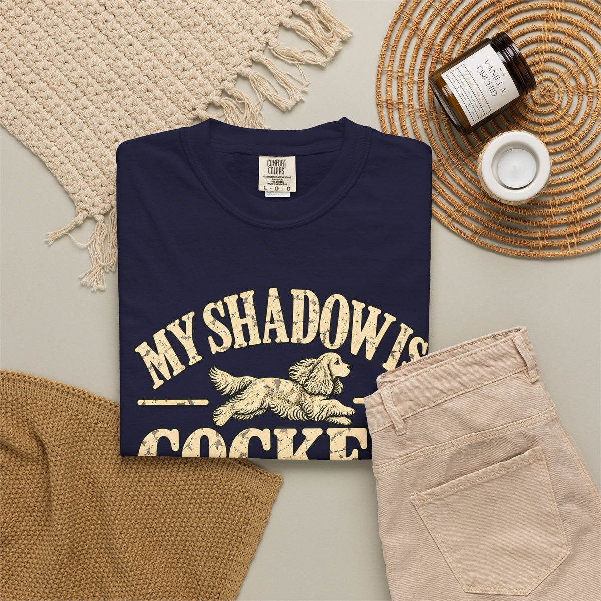 True Navy T-shirt with the Cocker Spaniel illustration and “My shadow is cocker shaped” lettering, styled with beige trousers and coffee.