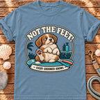 Front view of a Brinehound T-shirt showing a dog on a grooming table beneath Not the Feet lettering.