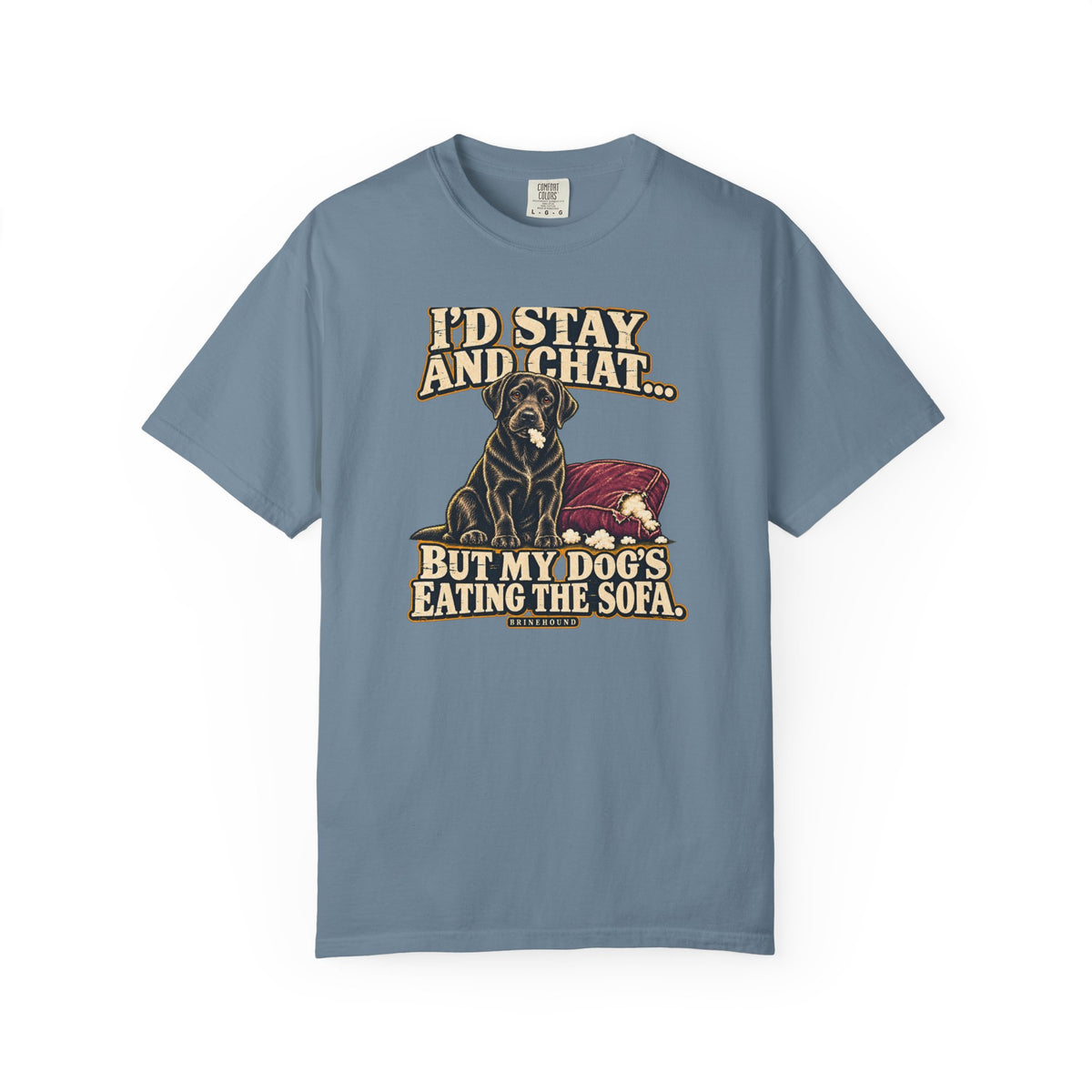 Front of a Ice Blue T-shirt with a vintage black Labrador beside a chewed sofa and “I’d stay and chat” lettering print.