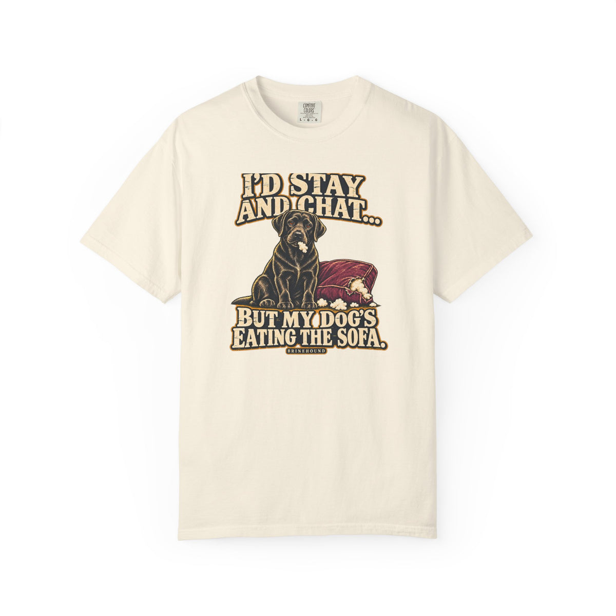 Front of a Ivory T-shirt with a vintage black Labrador beside a chewed sofa and “I’d stay and chat” lettering print.