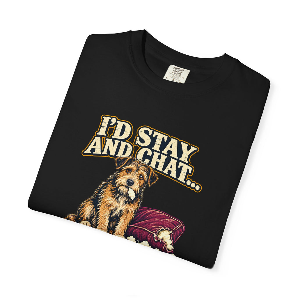 Folded Black T-shirt showing a close-up of the scruffy terrier beside a chewed sofa and “I’d stay and chat” lettering print.