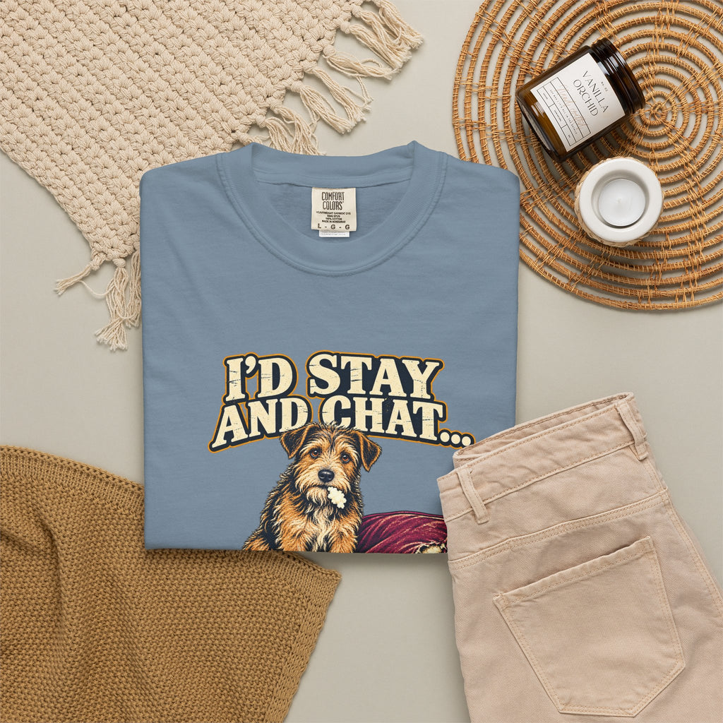 Ice Blue T-shirt with the scruffy terrier beside a chewed sofa and “I’d stay and chat” lettering print, styled with beige trousers and coffee.