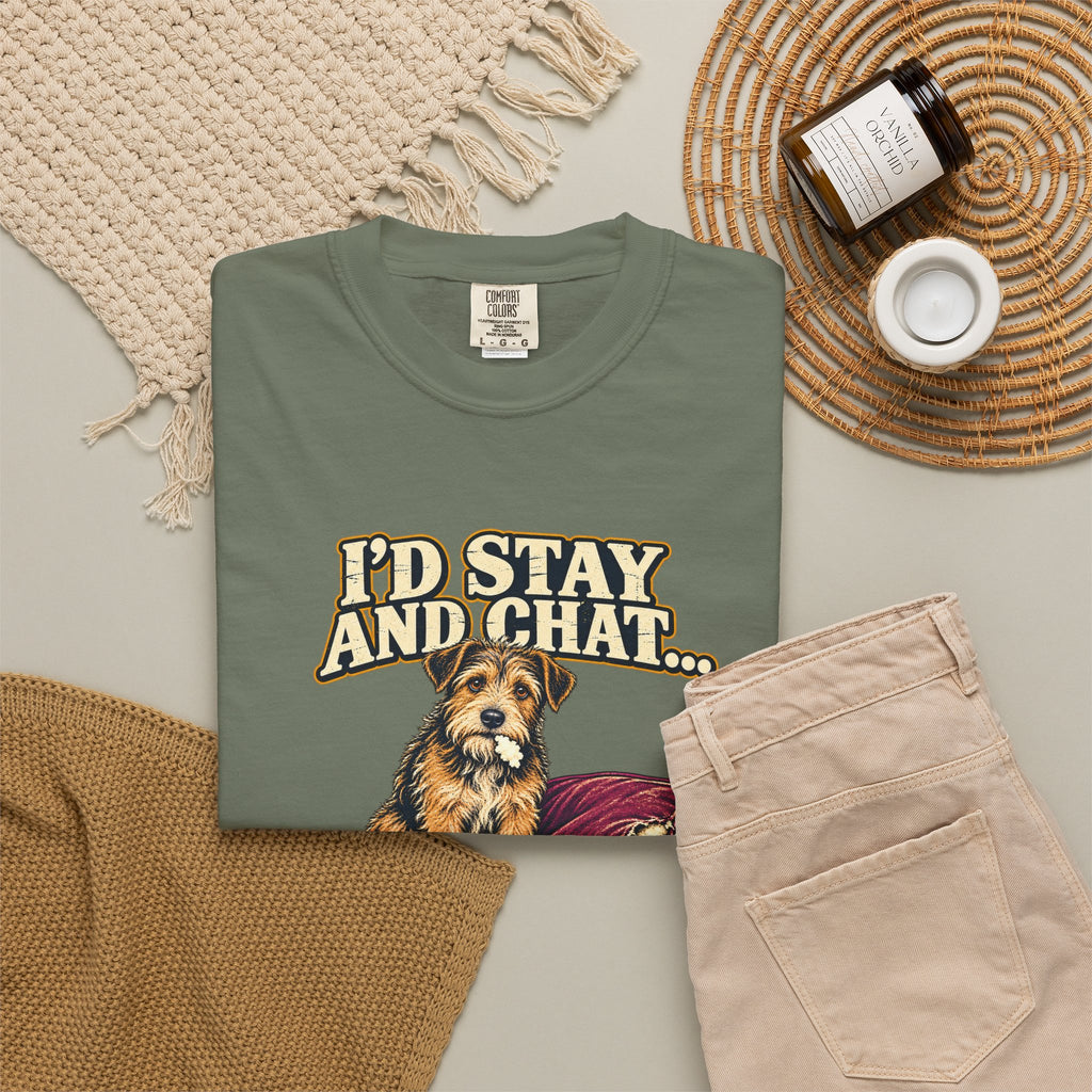 Moss T-shirt with the scruffy terrier beside a chewed sofa and “I’d stay and chat” lettering print, styled with beige trousers and coffee.