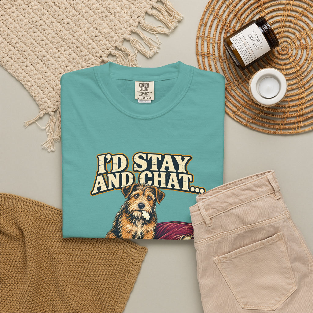 Seafoam T-shirt with the scruffy terrier beside a chewed sofa and “I’d stay and chat” lettering print, styled with beige trousers and coffee.