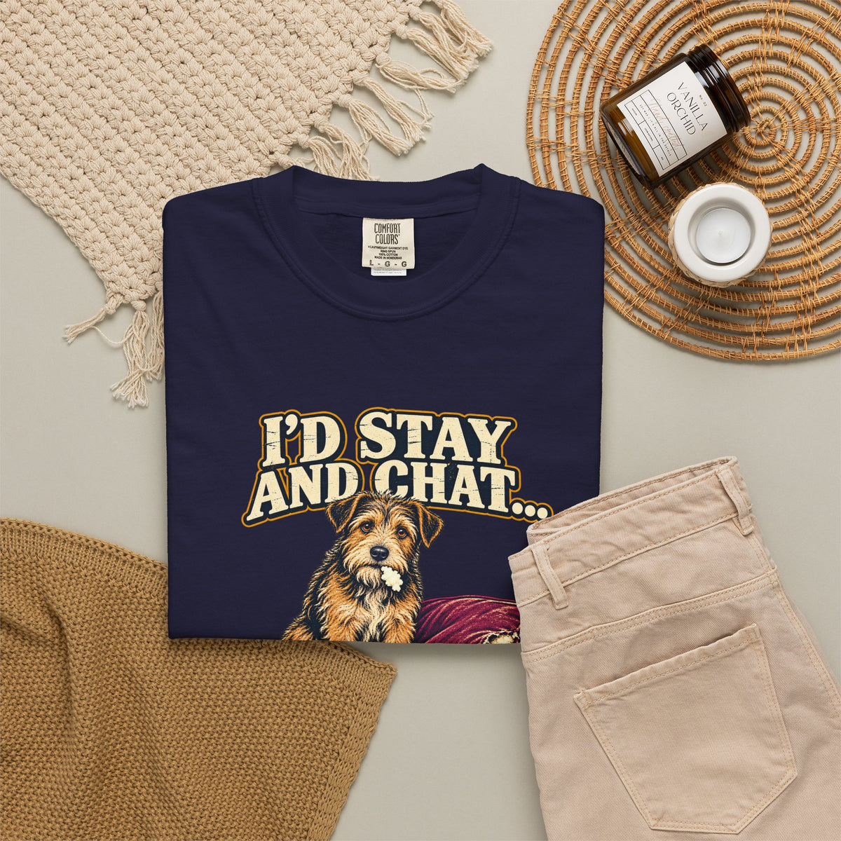 True Navy T-shirt with the scruffy terrier beside a chewed sofa and “I’d stay and chat” lettering print, styled with beige trousers and coffee.
